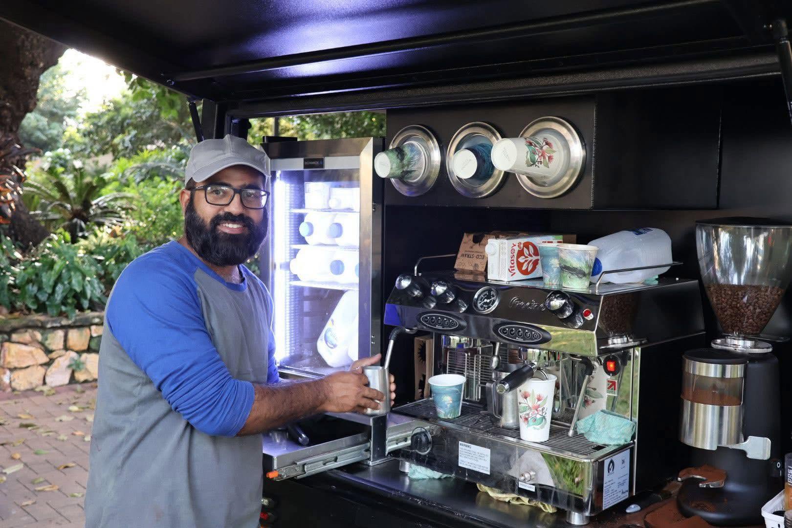 Sheraz steaming milk for a Blacklist Premium Coffee inside the van